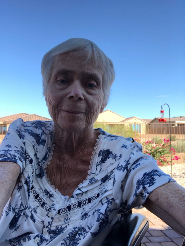 Woman with gray hair, bright blue sky in background.