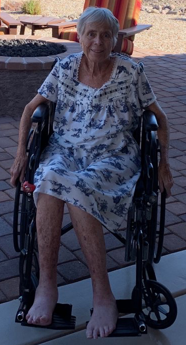 Woman with gray hair in wheel chair, bright blue sky in background.